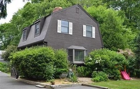 A house with a grey exterior and a red slide in the yard.