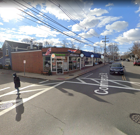 A street view with a crosswalk and a car driving on the road.