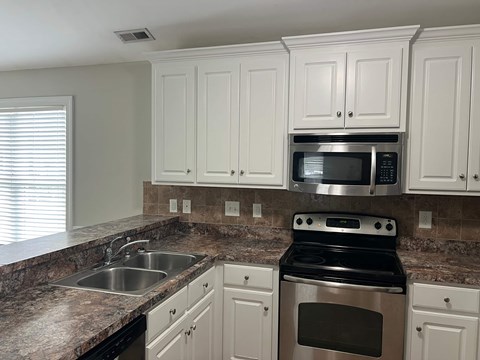 A kitchen with granite countertops and white cabinets.