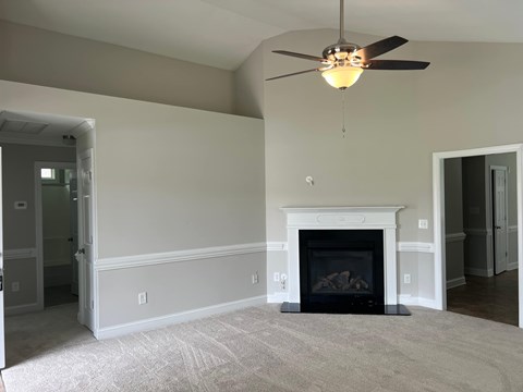 A living room with a fireplace and a ceiling fan.