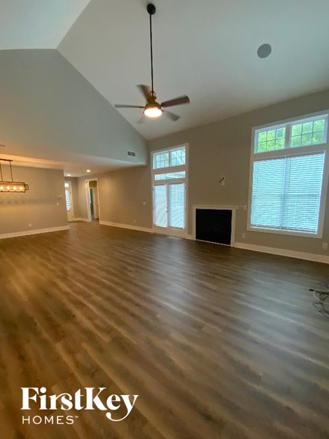 A spacious room with wooden flooring and a ceiling fan.