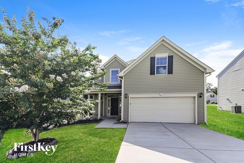 A house with a garage and a tree in front of it.