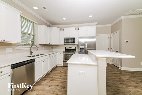 A kitchen with white cabinets and a stainless steel refrigerator.