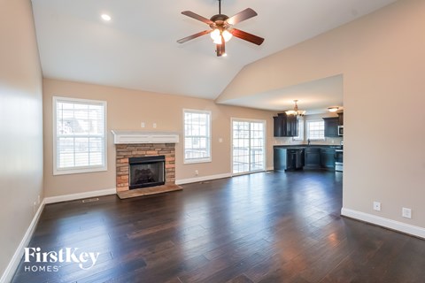 A spacious living room with a fireplace and a ceiling fan.