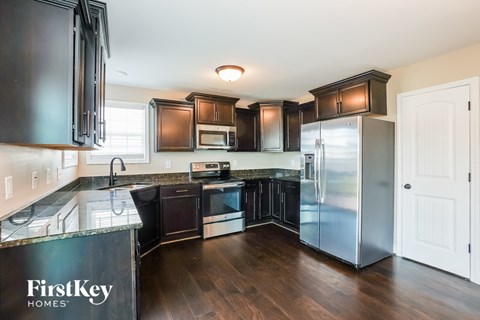 A kitchen with dark brown cabinets and a FirstKey Homes logo.