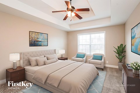 A bedroom with a large bed, a ceiling fan, and a painting on the wall.