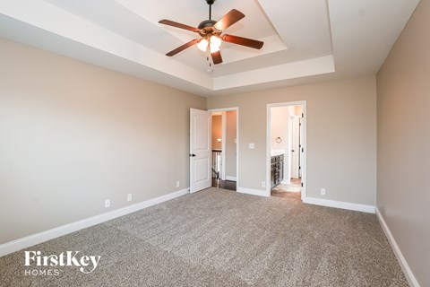 A spacious room with a ceiling fan and carpeted floor.