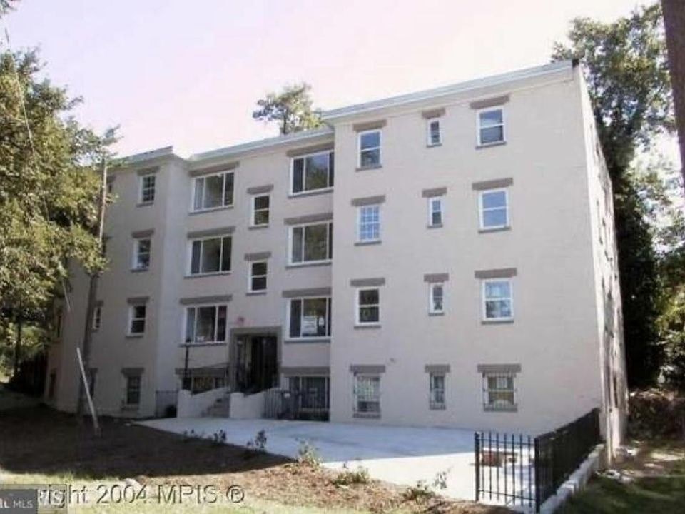 A tall building with many windows is surrounded by trees.