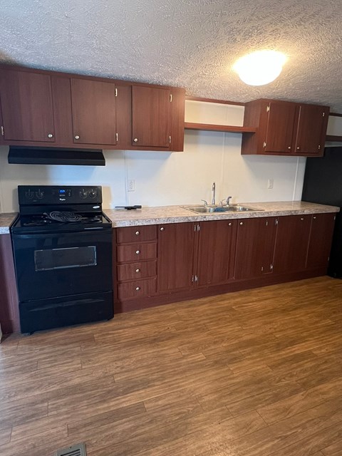 A kitchen with wooden cabinets and a black stove top oven.