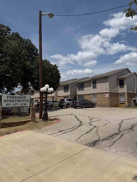 A sign for Parkside Apartments is in front of a building.