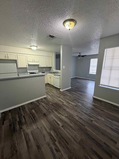 A kitchen with wood flooring and white cabinets.
