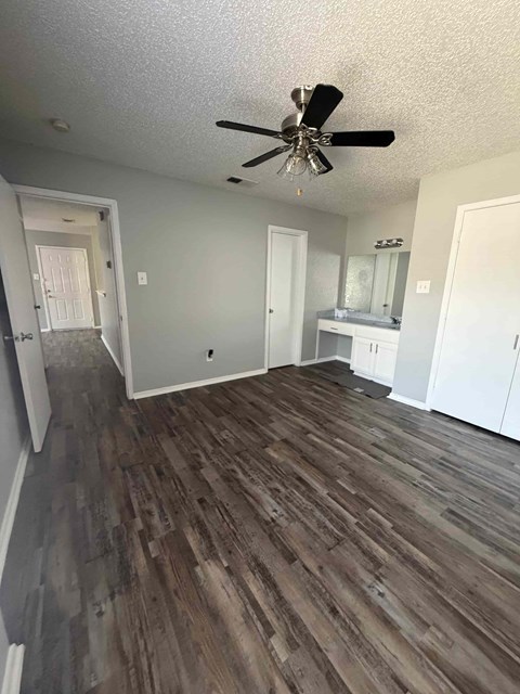 A room with a ceiling fan and wood flooring.