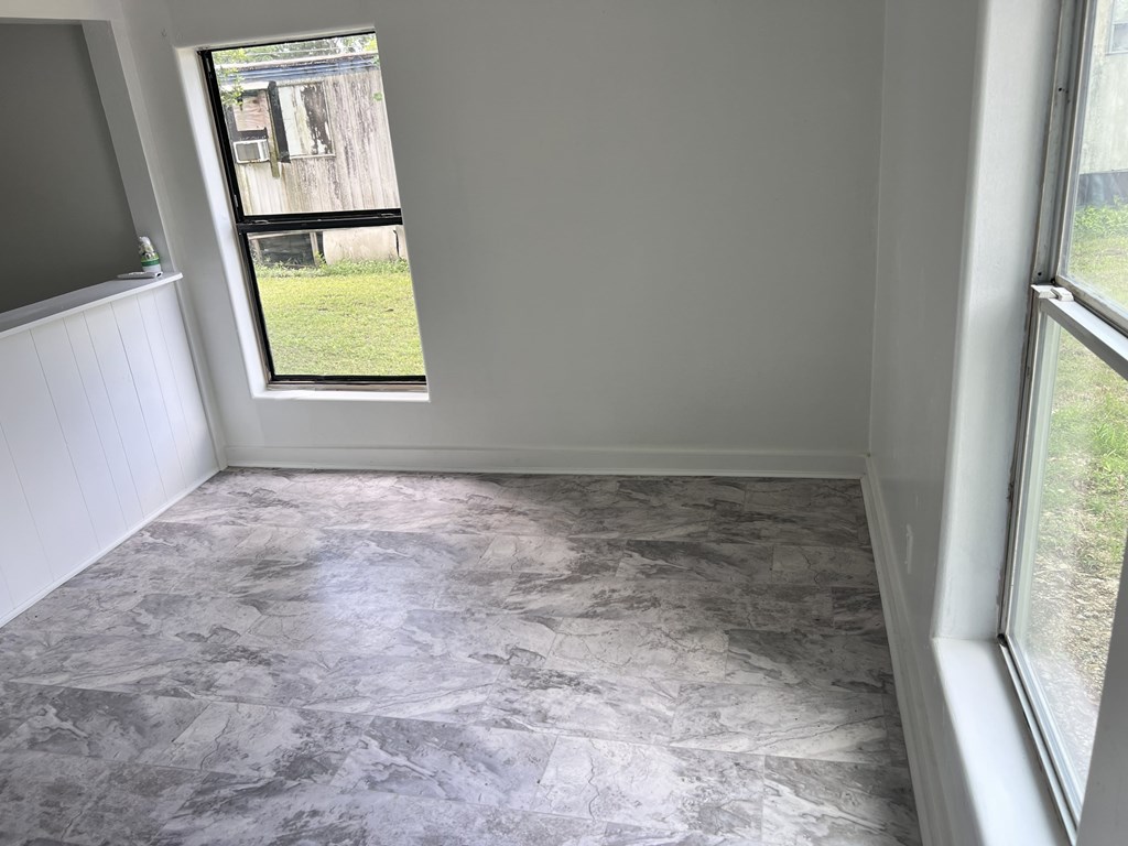 A room with a marble floor and a window overlooking a grassy area.