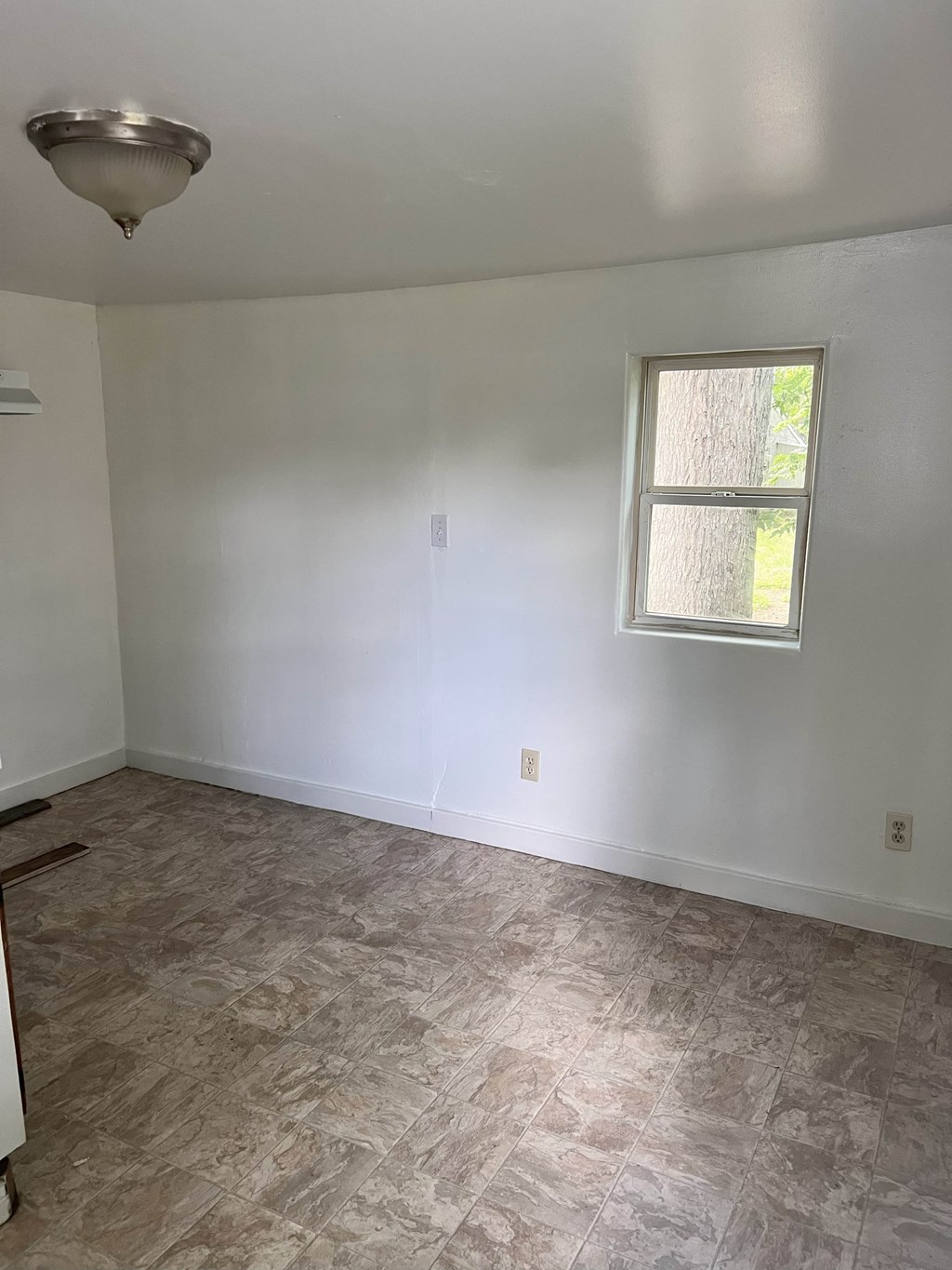 A room with a window and a light fixture on the ceiling.