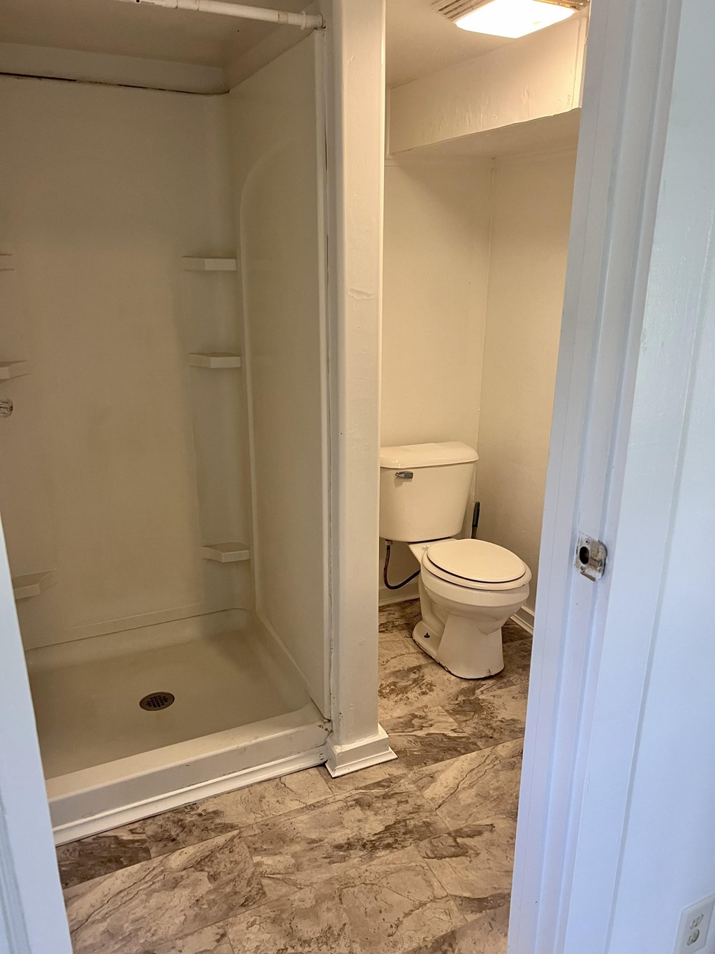 A white toilet sits in a bathroom next to a walk-in shower.