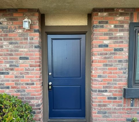 A blue door is set in a brick wall.