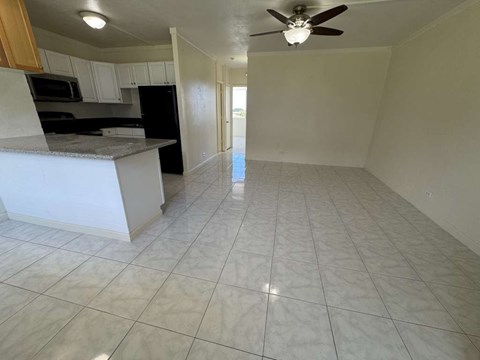 A kitchen with white cabinets and black appliances with a fan on the ceiling.