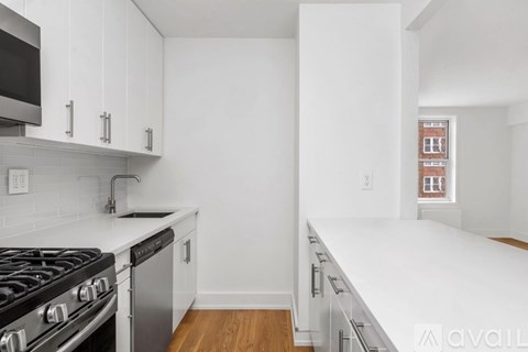 A kitchen with white cabinets and a stove top oven.