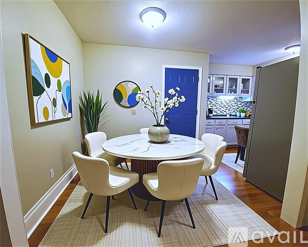 A living room with a couch, a chair, a dining table, and a painting on the wall.