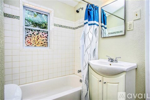 A bathroom with a white sink and a window with a view of trees.