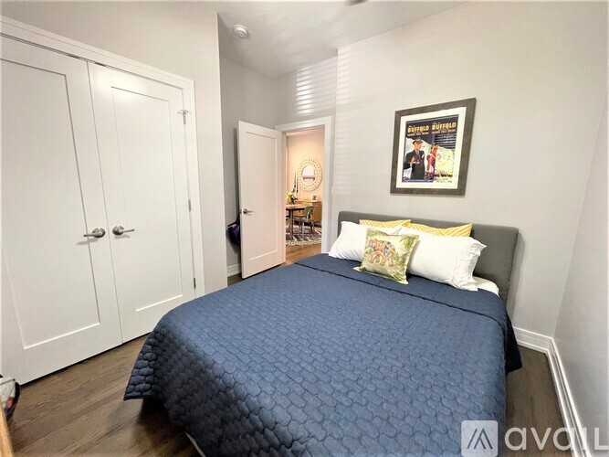 A bedroom with a bed, two pillows, and a picture on the wall.