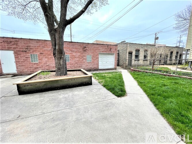 A tree in a planter sits in front of a brick building.