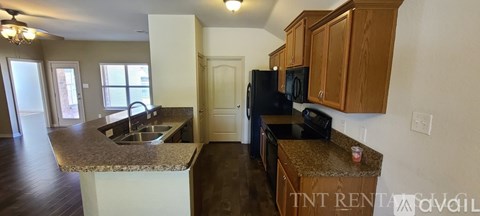 A kitchen with a black refrigerator and brown cabinets.