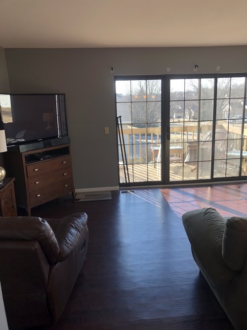 A living room with a brown leather couch and a television.