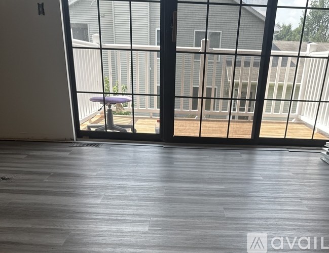 A room with a wooden floor and a view of a house through a glass door.