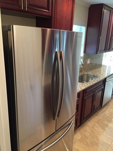 A stainless steel refrigerator in a kitchen with brown cabinets.