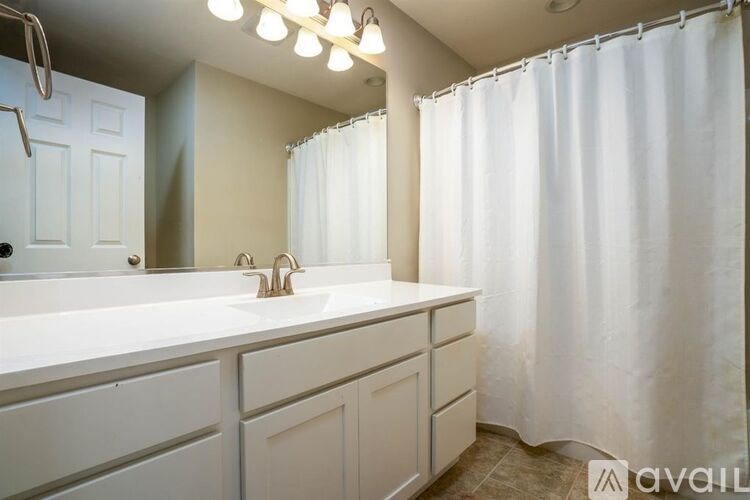 A white bathroom with a shower curtain and a sink.