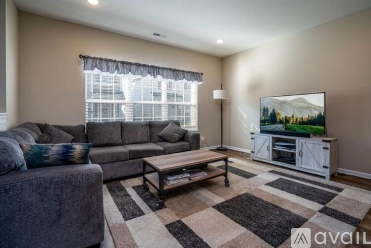 A living room with a grey couch, a coffee table, and a television displaying a forest scene.