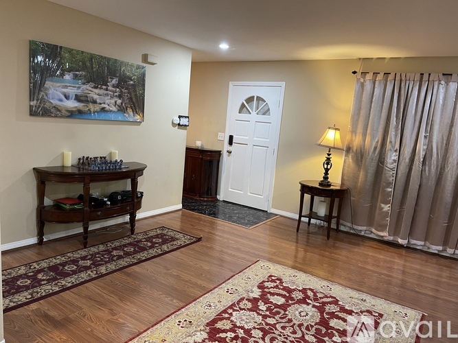A room with a painting of a waterfall on the wall and a chess set on a table.