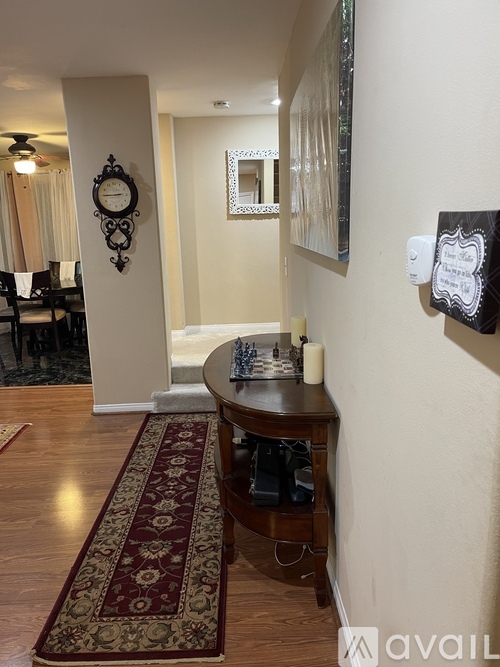 A hallway with a rug and a clock on the wall.