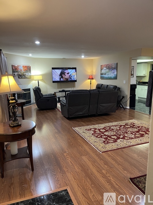 A living room with a couch, chairs, and a television.
