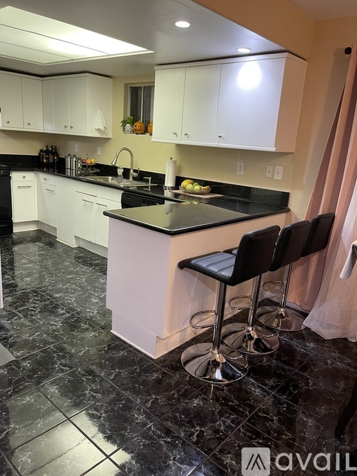 A kitchen with black marble floors and white cabinets.