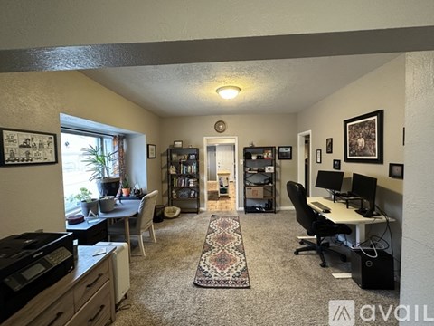 A living room with a rug in the middle and a dining table with chairs around it.