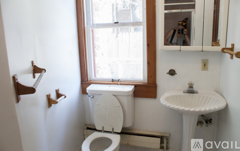 A bathroom with a toilet, sink, and mirror.