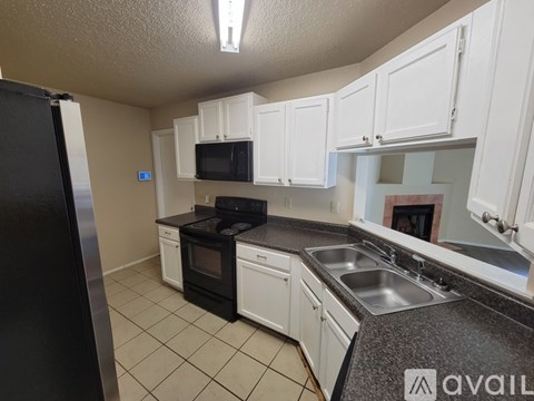 A kitchen with white cabinets and black appliances.