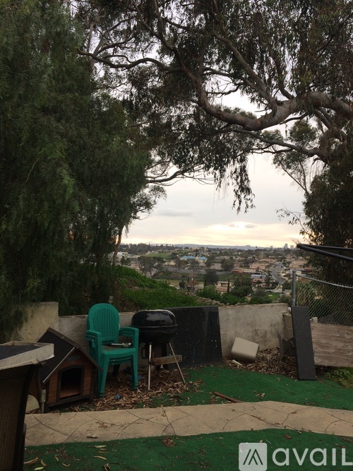 A patio with a green chair and a dog house.