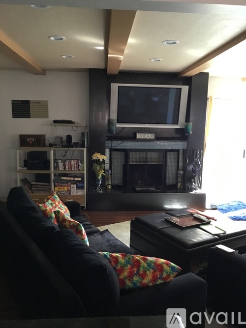 A living room with a black couch and a television on a stand.