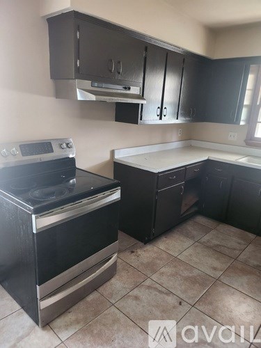 A kitchen with black cabinets and a stainless steel oven.