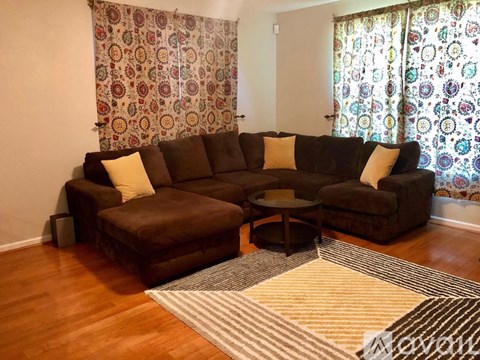 A living room with a brown couch and a round coffee table.