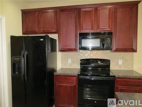 A kitchen with dark wood cabinets and black appliances.
