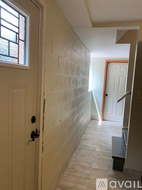 A hallway with a white door and a brick wall.