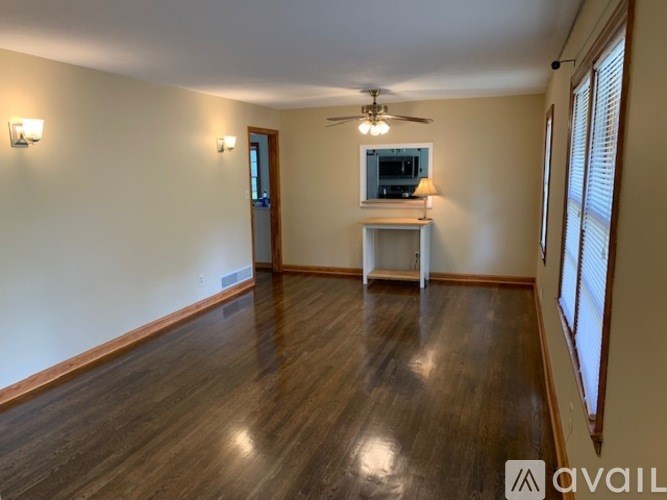 A spacious room with wooden flooring and a ceiling fan.