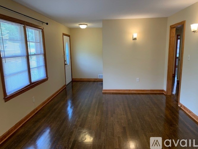 A room with wooden floors and a window with blinds.