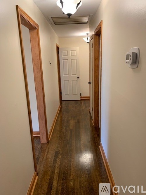 A hallway with a wooden floor and white walls.