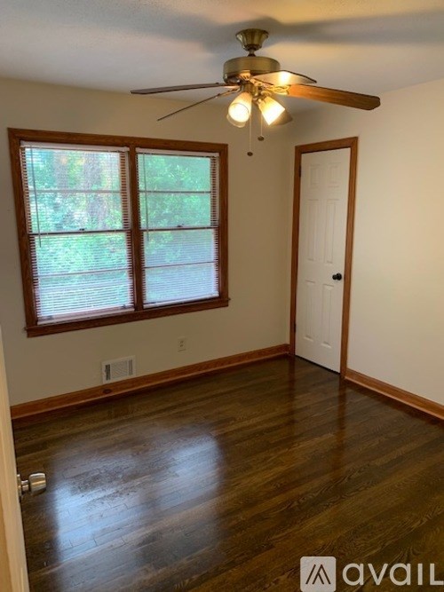 A room with a ceiling fan and a window with blinds.