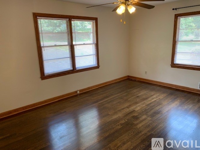 A room with wooden floors and two windows.